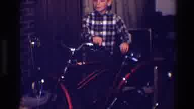 Toledo Ohio (1968): Boy In Checked Shirt Looks Over Bicycle Inside House Near