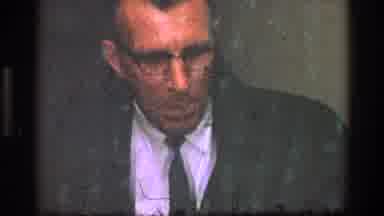 Toledo Ohio (1968): Man Wearing Grey Jacket And Glasses Talks To Off Screen Person