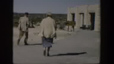 Texas (1951): People Walking To And From White Stone Building On A Sunny Windy Day