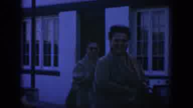Texas (1951): Women Wearing Tan Sweaters Walk Past White Building On A Windy Day