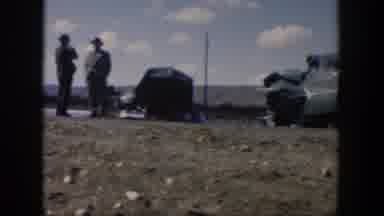 Texas (1951): Four Men Changing Tire Of Green Car On A Clear Day