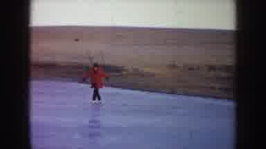 North Dakota (1953): Woman Wearing Red Coat Skates On Frozen Pond On A Clear Day