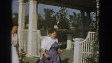 Los Angeles California (1961): Woman Wearing Blue Dress Walks Past White Gate On A