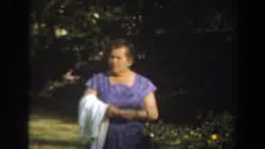 Los Angeles California-1961: Woman in Purple Dress Strolling Through Garden