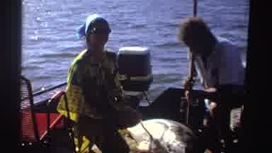 Nigeria (1969): Couple Looks At Grey Object In Boat On A Sunny Day