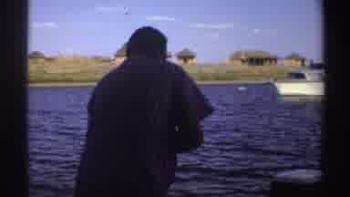 Nigeria (1969): Fishermen Gathered In A Boat Fishing On The River With Houses In