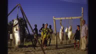 Nigeria (1969): Fish Hanging In African Village With People Gathered Around It