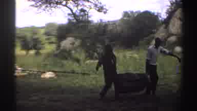 Nigeria (1969): Men Carrying Something Heavy In The Middle Of The Field