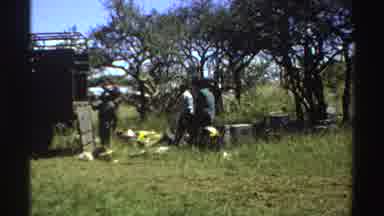 Nigeria (1969): People Unloading Goods From A Truck In A Grassy Field That Has