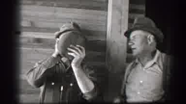 California (1939): Two Men Sharing A Drink From A Jug In Front Of A Wood Building