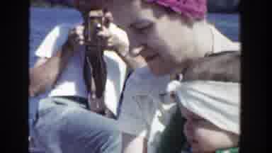 Wisconsin (1953): Woman Wearing Pink Hat Picks Up Small Girl Wearing White Scarf