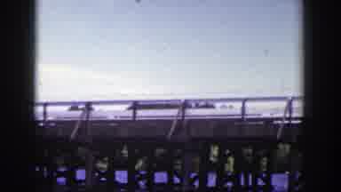 Wisconsin (1953): View Of Cars Crossing Brown Wooden Bridge On A Clear Sunny Day