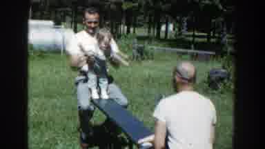 Wisconsin (1953): Two Men With Their Babies Are Playing Seesaw In Garden