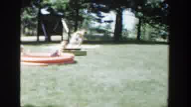 Wisconsin (1953): Adults Standing In A Large Grassy Yard While Children Play In A