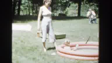 Wisconsin (1953): Woman Wearing White Pants Watches Toddlers Play In Orange Kiddie