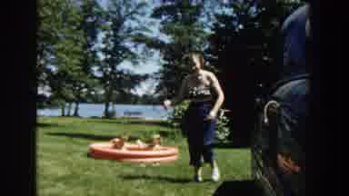 Wisconsin (1953): Woman Wearing Blue Pants Watches Toddler Wearing Brown Shorts