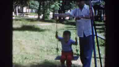 Wisconsin (1953): Parent Pushing A Young Child On A Rope And Wood Swing In Grass