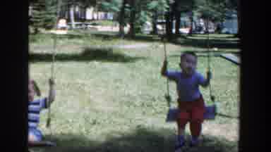 Wisconsin (1953): Two Kids Play On Red Metal Swing set On A Bright Sunny Day