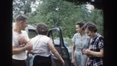 Wisconsin (1953): Four People Stand Near Blue Car Talking And Laughing On A Clear