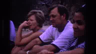 Utah (1969): A Woman Smiles Next To People Sitting On The Sand