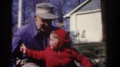 Pequot Lakes Minnesota (1964): Man Wearing Blue Jacket Rides Object With Toddler