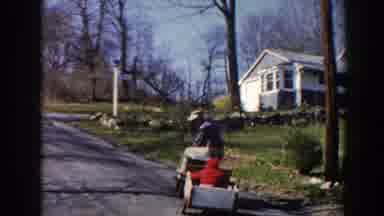 Pequot Lakes Minnesota (1964): A Man Playing With His Kid Riding On A Toy Car