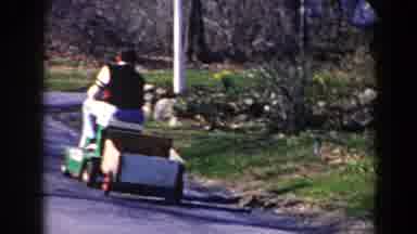 Pequot Lakes Minnesota (1964): A Man Is Driving His Lawnmower Down A Street