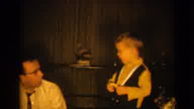 Pequot Lakes Minnesota (1964): A Man Sitting And Facing A Young Boy Standing And