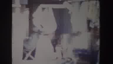 South Africa (1969): Person Wearing Green Hat Points At Dark Grey Item At Outdoor