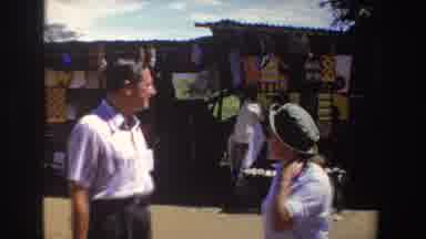 South Africa (1969): Man And Woman In Outdoor Marketplace Buying Souvenirs From