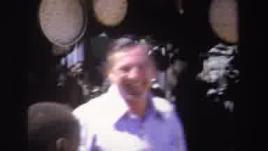 South Africa (1969): Man Wearing Blue Shirt Holds Up Red Object At Outdoor Market