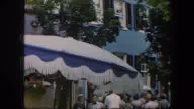Baltimore Maryland (1960): Crowds Standing Near Blue And Red Buildings On A Sunny