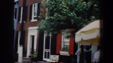 Baltimore Maryland (1960): Two Women Stand Under Yellow Umbrella Near Red Building