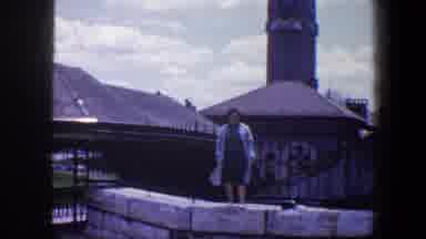 Baltimore Maryland (1960): A Woman Wearing A Dress And Trench Coat Stands On A