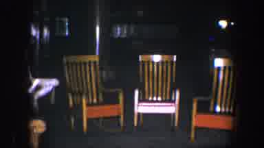 BALTIMORE MARYLAND-1960: Three Brown Rocking Chairs With Orange Seats In Dark Room
