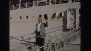 Nassau Bahamas (1961): Man Wearing Grey Jacket Walks Down White Ramp Holding Straw