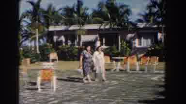 NASSAU BAHAMAS-1961: Two Women Walking Together in Classic Dresses Near Tropical Resort