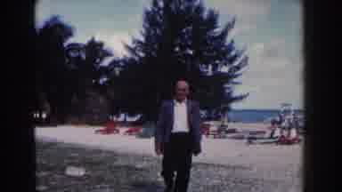 NASSAU BAHAMAS-1961: A Man In A Blazer Joined By A Woman In A Dress Walks On A