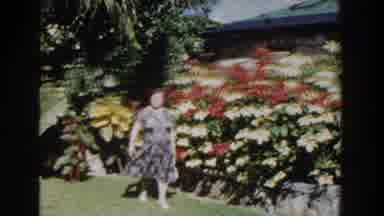 Nassau Bahamas (1961): Smiling Woman With Purse Strolls Through A Garden On A