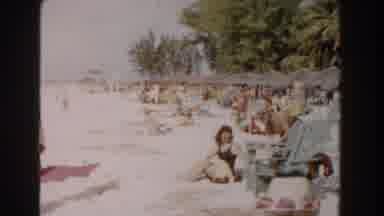 Nassau Bahamas (1961): Woman Wearing Brown Dress Waves At Camera While Standing