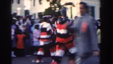 Nassau Bahamas (1961): Crowds Watch As Costumed Figures March Down The Road During
