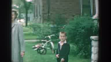 Wisconsin (1964): A Woman In A Nice Jacket Walks Out Of The House With Her Son