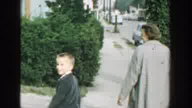 Wisconsin (1964): A Woman In A Nice Jacket Walks Out Of The House With Her Son