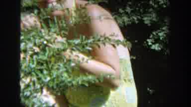 Wisconsin (1964): Woman Smiling While Hiding Behind A Bush In The Garden