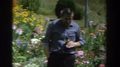 Wisconsin (1964): Man Is Standing In A Flowery Garden Near A River