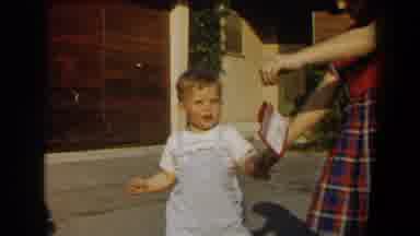 California (1958): Toddler Wearing Blue Overalls Follows Girl Wearing Red Dress On