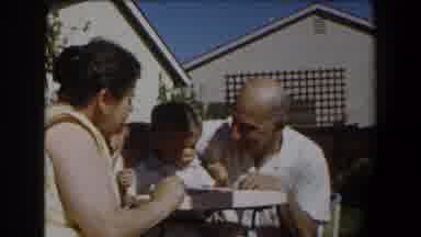 California (1958): Infant In A Highchair Eats Out Of His Father's Hand While His