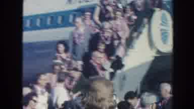 Hawaii-1961: Well-Dressed Men And Women Wearing Leis Descend Airplane Stairs