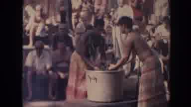 Hawaii (1961): Men Wearing Red And Yellow Sarongs Remove Hot Items From Gray Pot