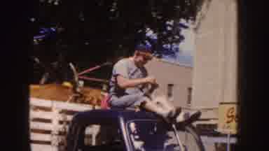 South Dakota (1954): Person Riding On Top Of Car While Others In Costume Walk